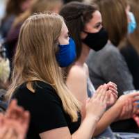 Audience wearing masks, applauding.